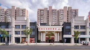 A multi-story hotel with a central entrance, surrounded by other buildings. - Vienna International Hotel (Shanghai)