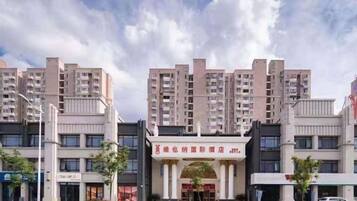 Ein mehrgeschossiges Hotel mit einem zentralen Eingang, umgeben von anderen Gebäuden.