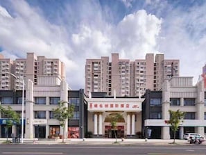 A multi-story hotel with a central entrance, surrounded by other buildings. - Vienna International Hotel (Shanghai)