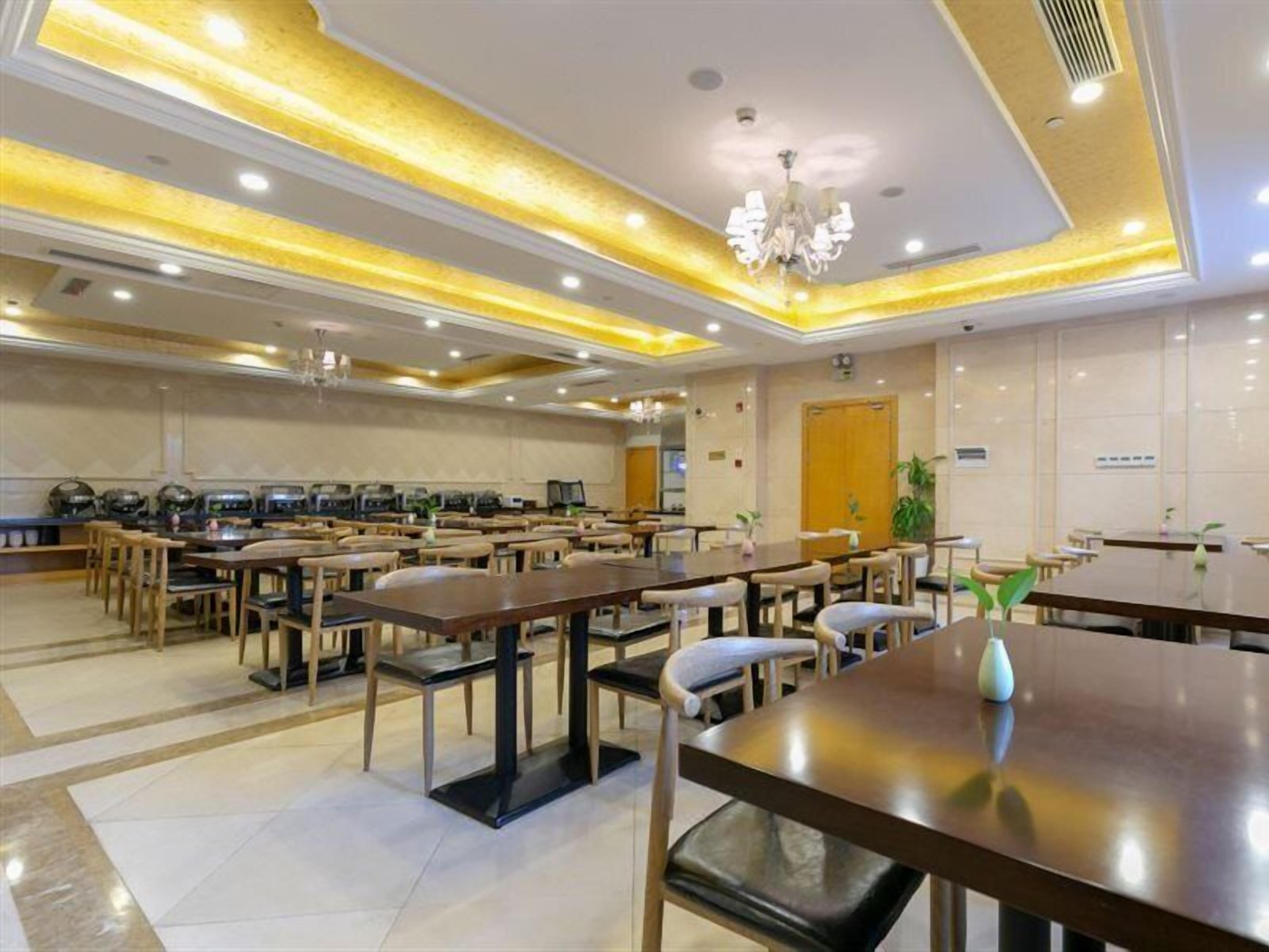 Ein Hotelrestaurant mit mehreren Tischen und Stühlen, einer Kandelaber und einem klaren, modernen Design.