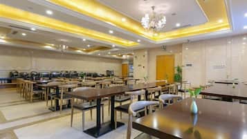 Ein Hotelrestaurant mit mehreren Tischen und Stühlen, einer Kandelaber und einem klaren, modernen Design.