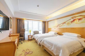 A hotel room with two beds, a desk, a chair, a TV, and a painting on the wall. - Vienna International Hotel (Shanghai)
