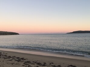 A beach with calm waters and a clear sky.