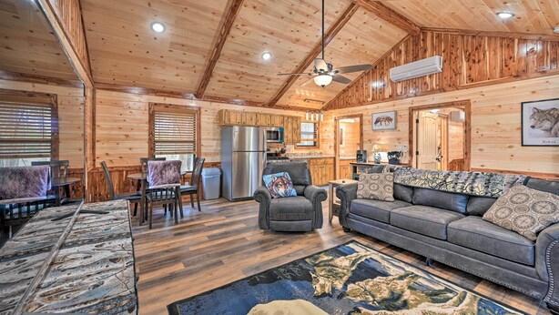 A log cabin interior with a dining area, kitchen, and seating with a fireplace. - Cozy Broken Bow Cabin, Walk to the Lukfata Creek! (Broken Bow)
