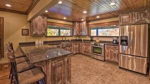 A spacious kitchen with wooden cabinets, a granite countertop, stainless steel appliances, and a large island with bar stools.