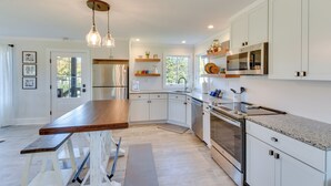 A modern kitchen with white cabinetry, stainless steel appliances, and a wooden island. - Modern Clarkesville Cottage w/ Decks & Patio! (Clarkesville)