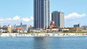 En hög byggnad med en skylt som visar texten ”Atlantic Palace” och en strandpromenad med folk och strandparasoller.