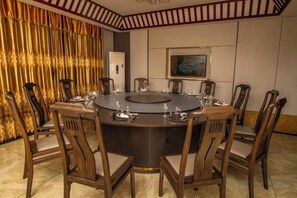 A round table with chairs, a painting on the wall, and a curtain with a pattern. - Lingzhou International Hotel (Fang County)