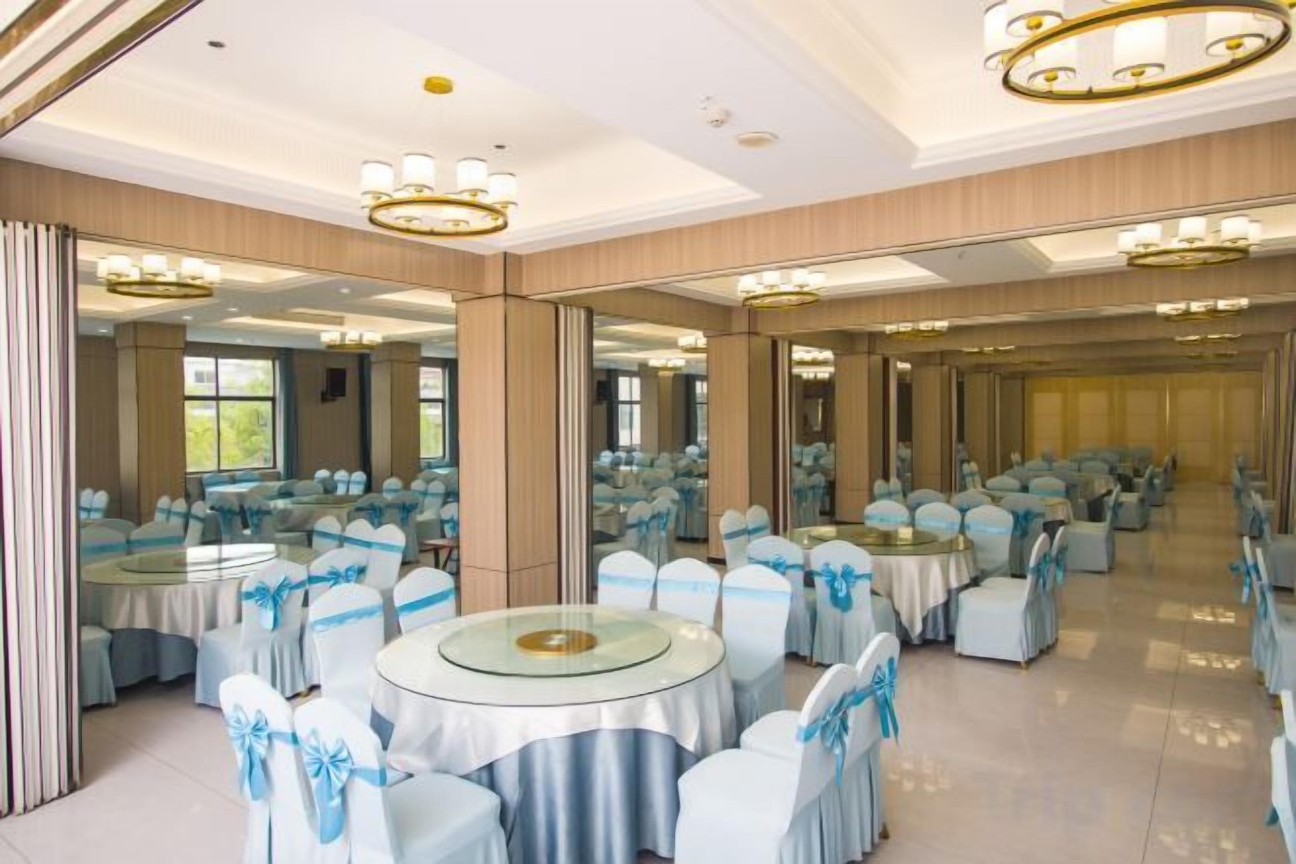 A banquet hall with round tables, chairs, and a mirrored wall.