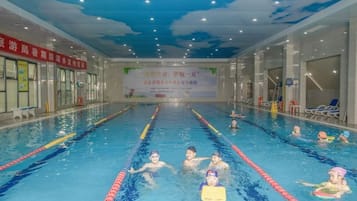 An indoor swimming pool with lanes, lifeguard chairs, and a banner on the wall.