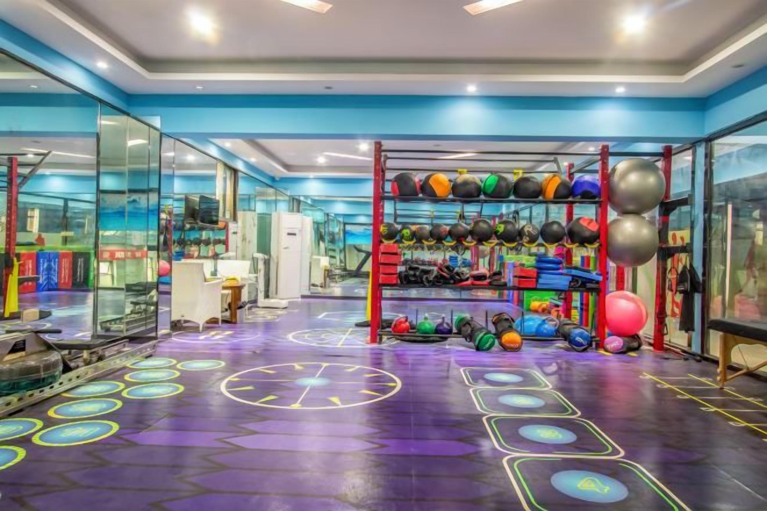 A gym with exercise equipment and a colorful floor layout.