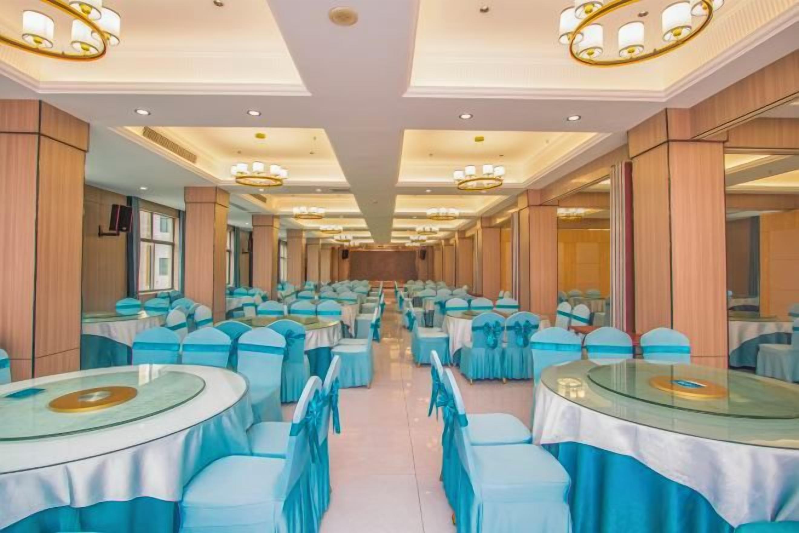 A banquet hall with round tables and chairs, a long corridor, and a mirrored wall.