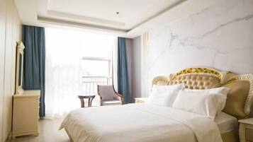 A hotel room with a large bed, a chair, a nightstand, and a view of the outdoors.