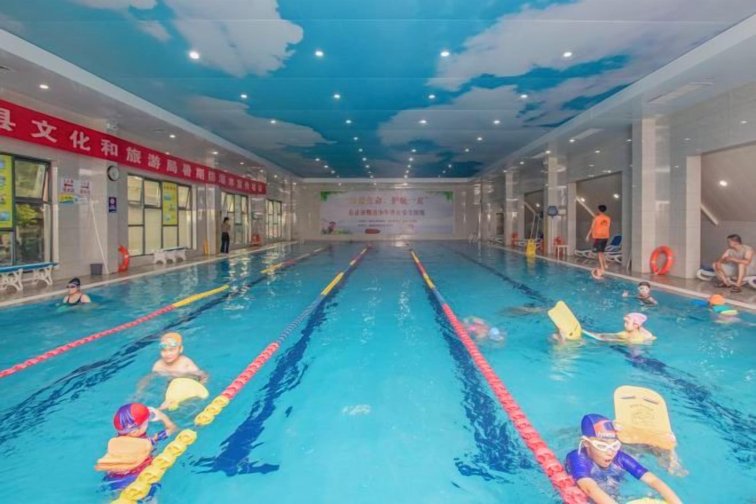An indoor swimming pool with lanes, lifeguard chairs, and swimmers.