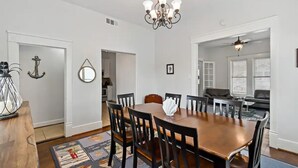 A dining area with a wooden table and chairs, a chandelier, and a patterned rug. - The Urchin - Quick stroll to the beach!!! (Galveston)