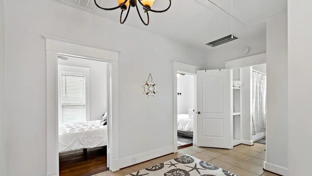 A spacious room with a large bed, a ceiling fan, and a patterned rug. - The Urchin - Quick stroll to the beach!!! (Galveston)