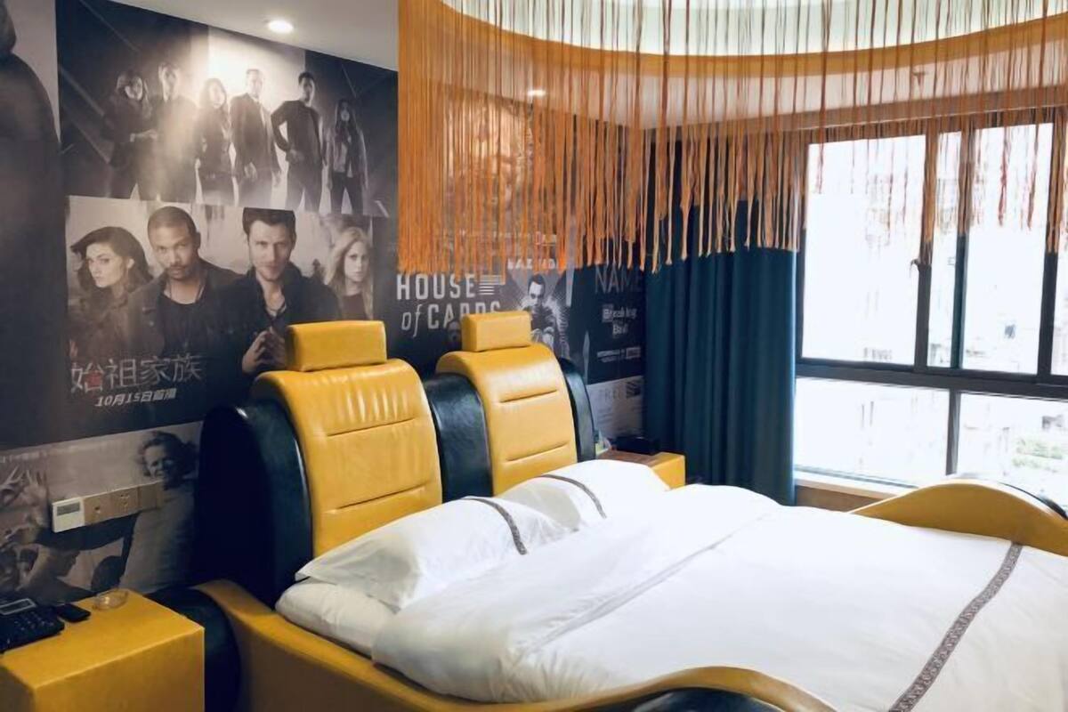 Una habitación de hotel con cama, mesita de noche y un cartel en la pared.