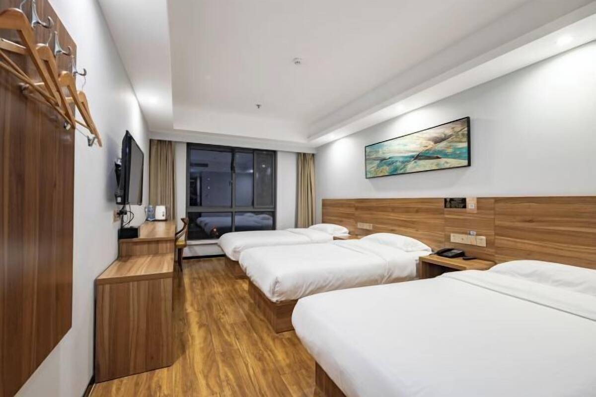 Habitación de hotel con dos camas, un escritorio de madera, un televisor y un cuadro en la pared.