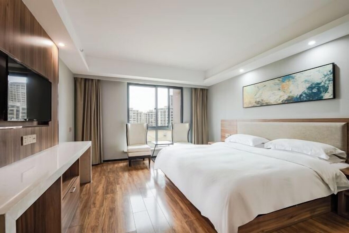 Habitación de hotel con una cama grande, televisión de pantalla plana, escritorio y ventana con cortinas.