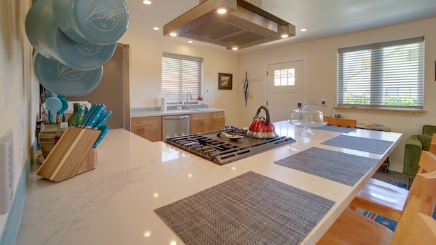 Een moderne keuken met een centraal eiland, ingebouwde kookplaat en afzuigkap.