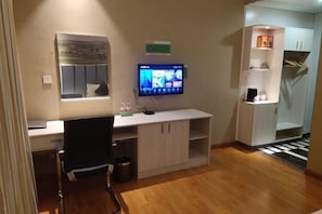 Une chambre moderne équipée d’un bureau, d’un téléviseur à écran plat, d’une chaise et d’une petite poubelle.