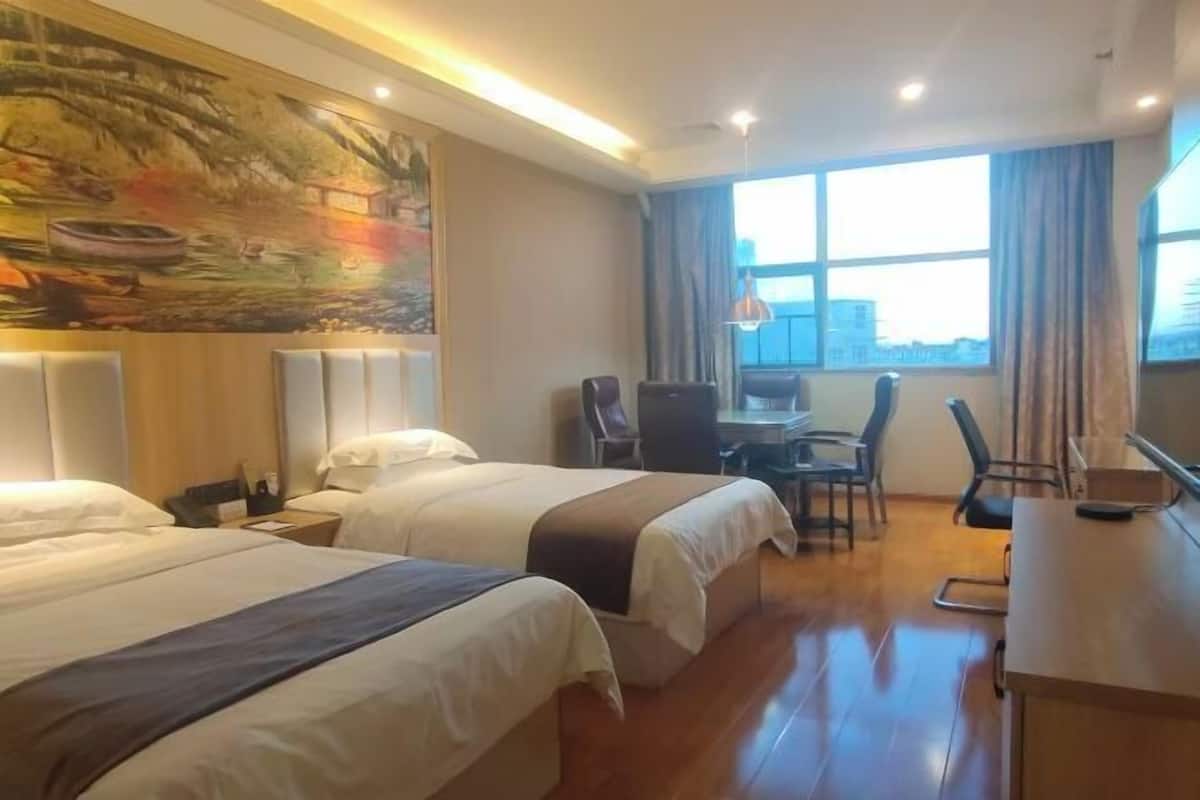 Ein Hotelzimmer mit zwei Betten, einem Schreibtisch, einem Stuhl und einem großen Fenster mit Blick.