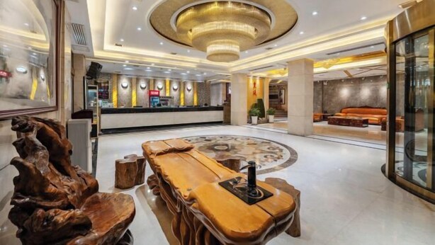 Eine moderne Lobby mit einer zentralen Holzbänklage, einer runden Sitzecke und einem großen Chandelier.