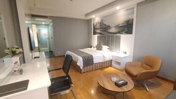 A modern hotel room with a bed, a desk, a chair, and a round table.
