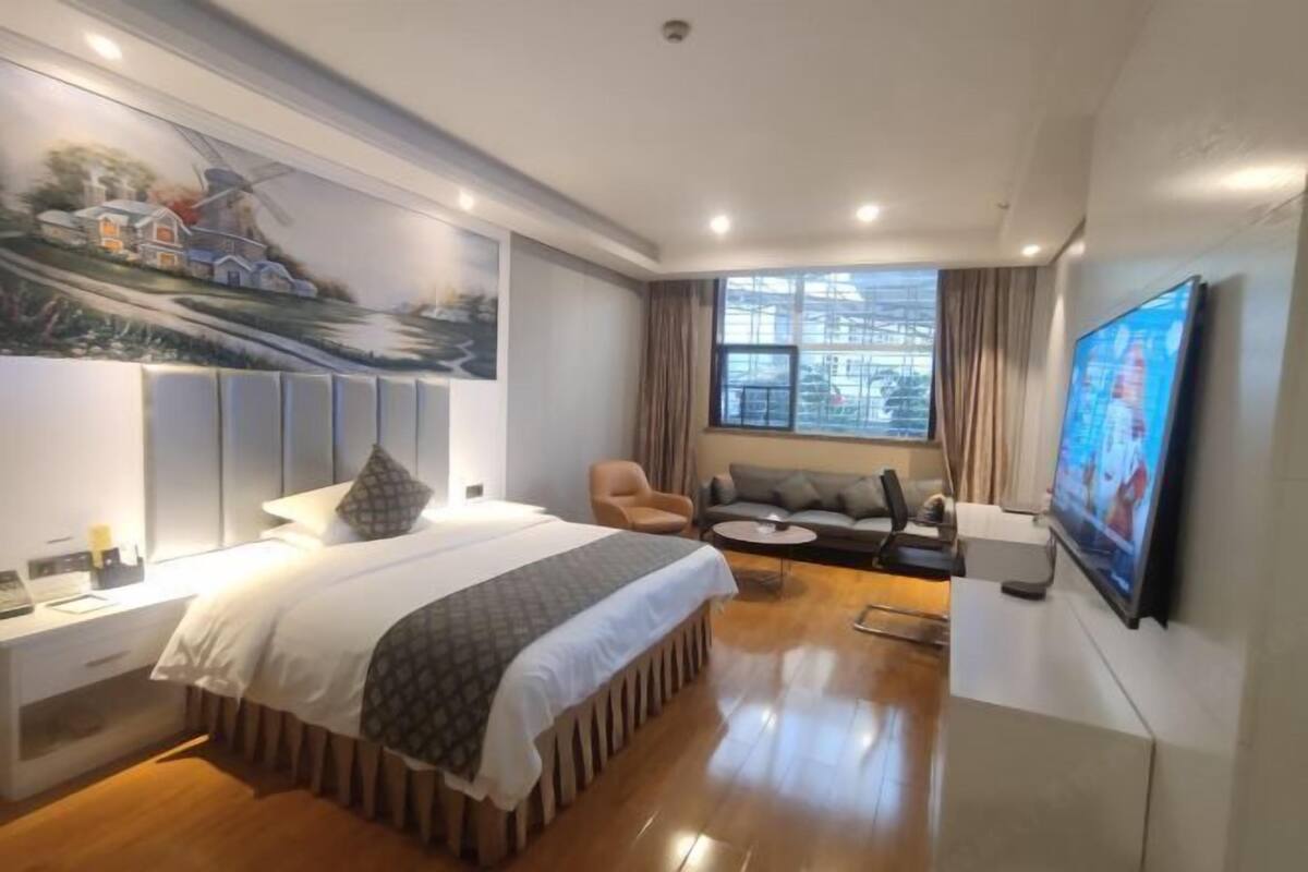 Ein Hotelzimmer mit Bett, einer Couch, einem Fernseher und einem Bild an der Wand.