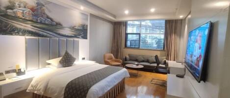 A hotel room with a bed, a sofa, a TV, and a painting on the wall.