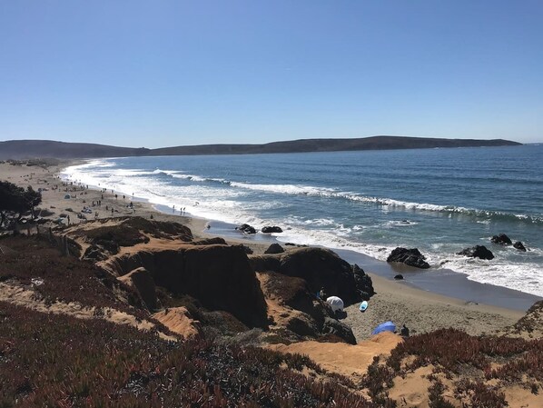 A coastal beach with rocky terrain and a clear view of the ocean.