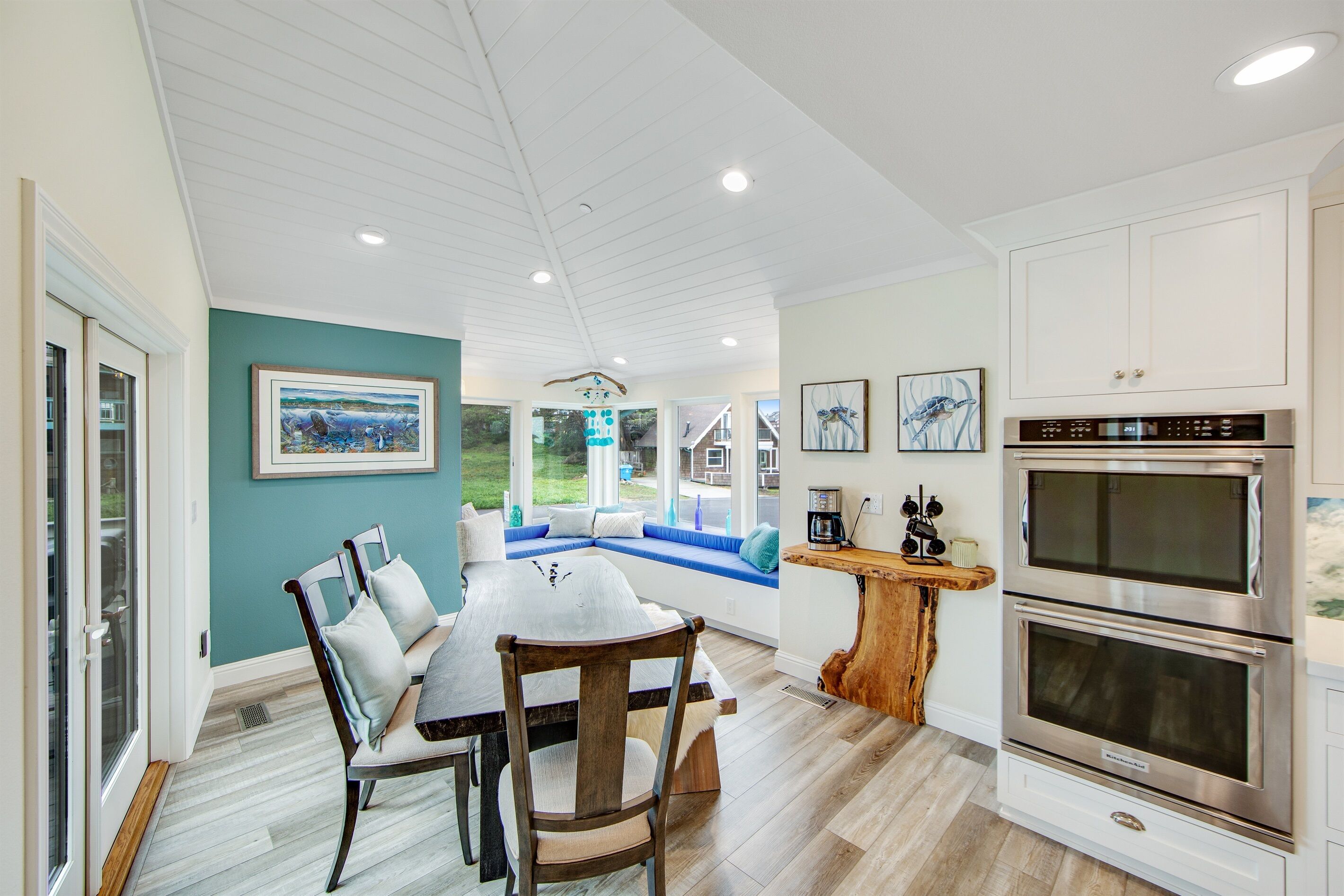 A modern kitchen with white cabinetry, stainless steel appliances, and a dining area with a wooden table and chairs.