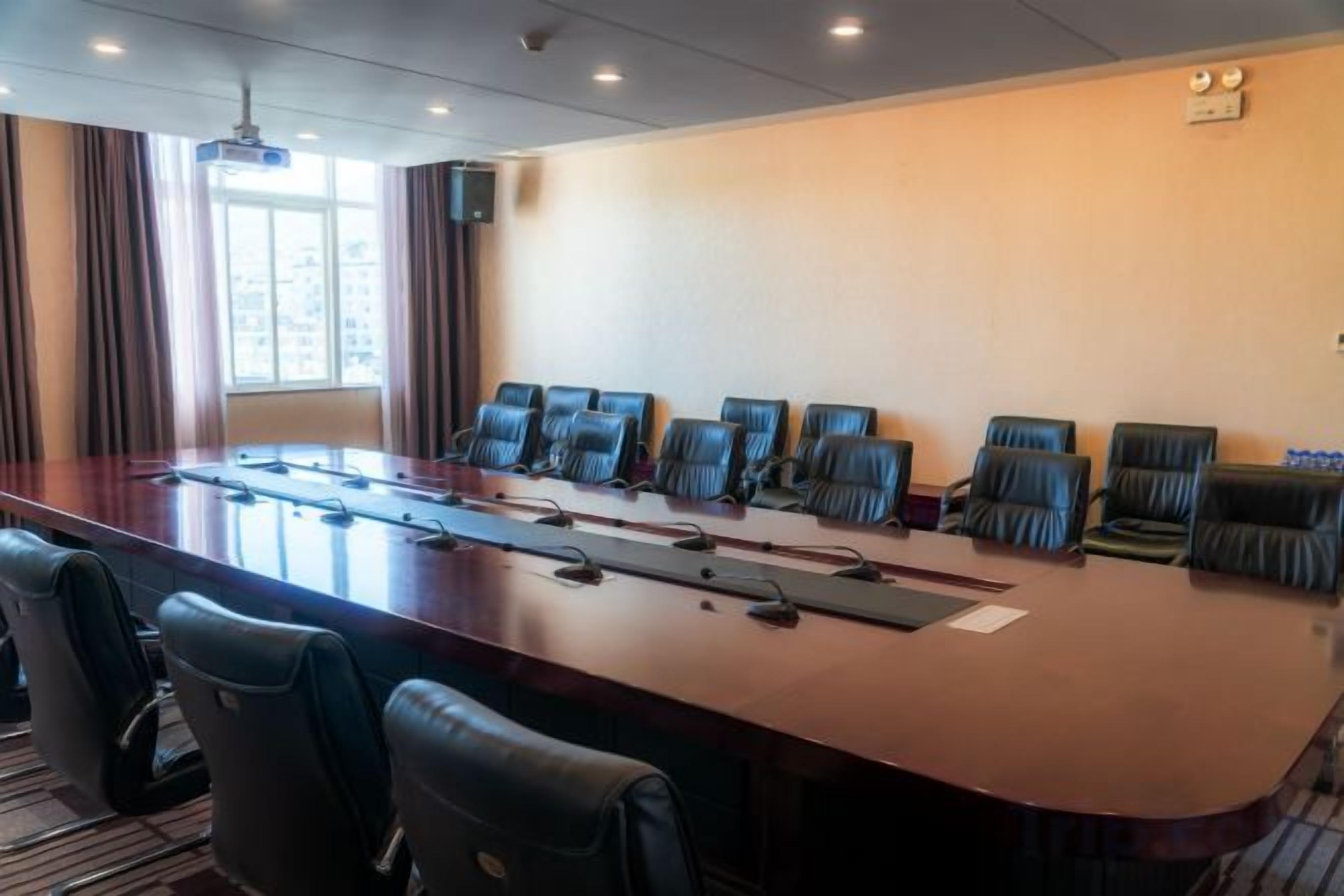 A conference room with a long table, multiple chairs, and a projector.