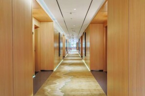 A long, narrow hotel corridor with wooden walls and a patterned carpet. - Jinyu Hotel (Weixi)