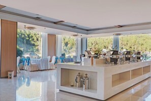 Un lobby espacioso con mostrador de recepción, zona de estar y grandes ventanales con vistas al exterior.