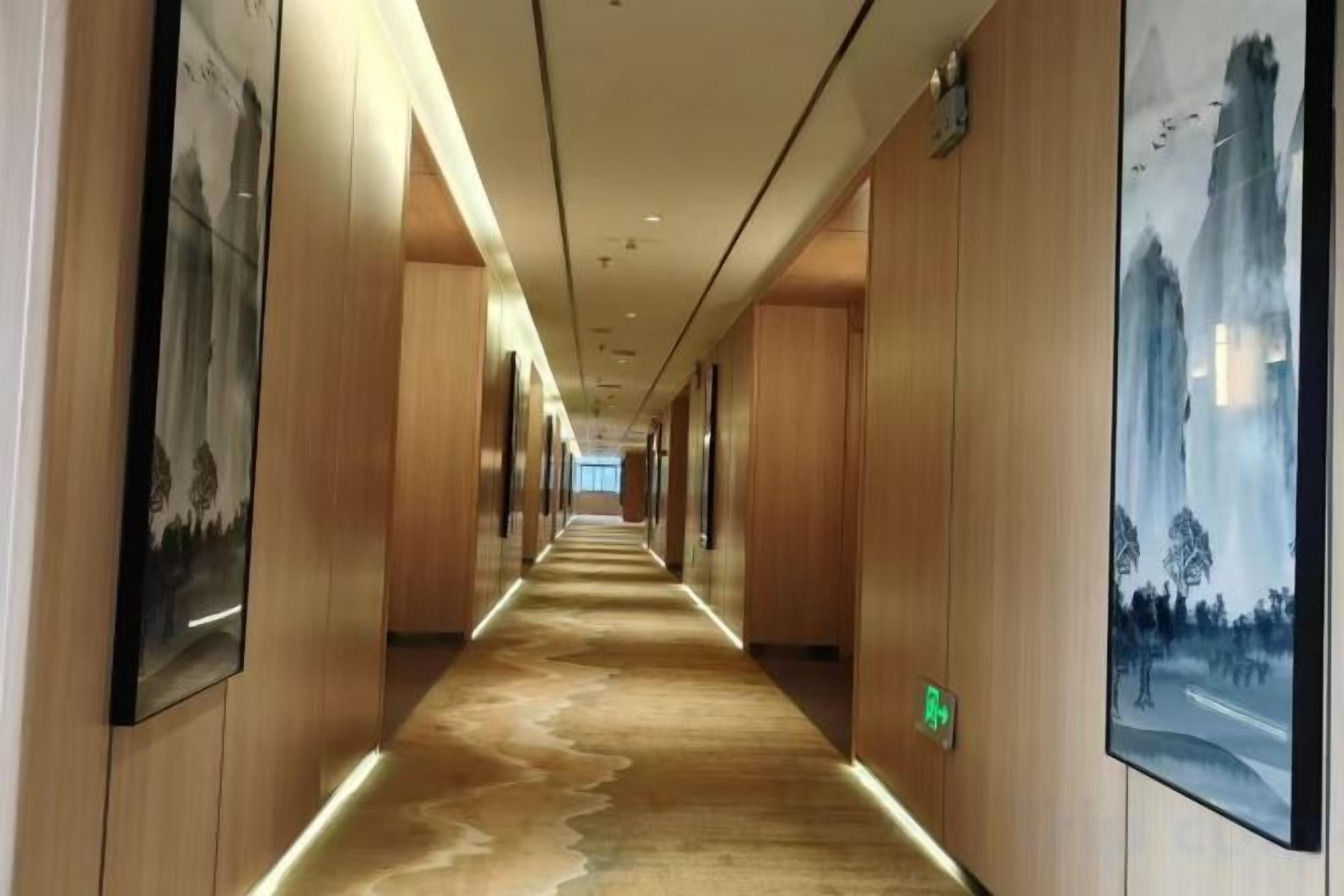 A long hallway with wooden paneling and artwork on the walls.