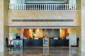 A hotel reception area with a marble reception desk, two receptionists, a balcony with a railing, and a clean, polished floor. - Jinyu Hotel (Weixi)