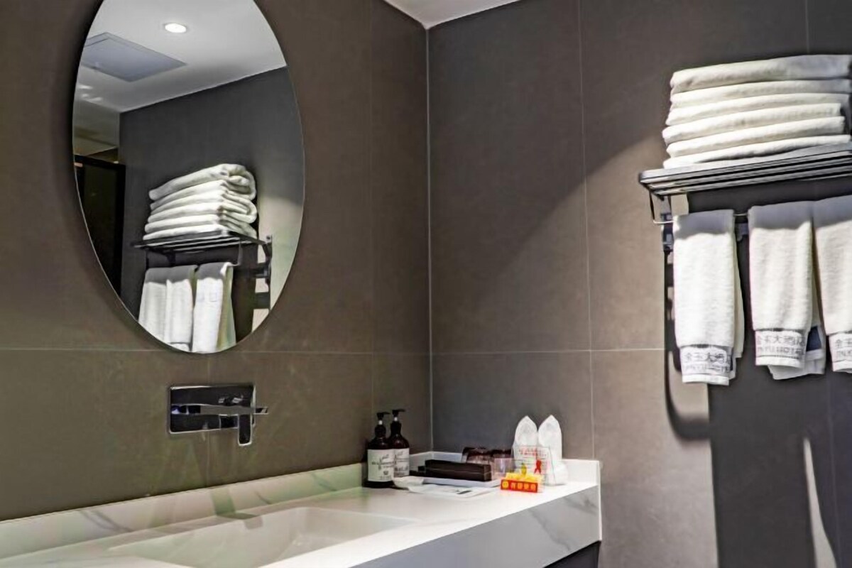 Un baño moderno con un espejo grande, un lavamanos y toallas ordenadamente dobladas.
