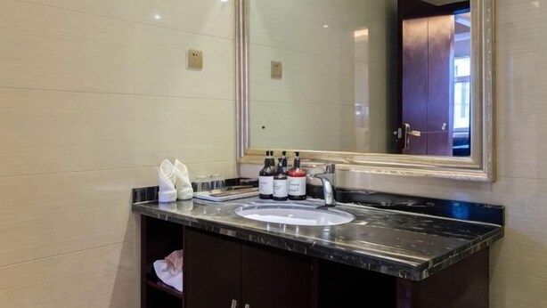 Un baño con un espejo grande, un lavamanos y artículos de aseo en la encimera.