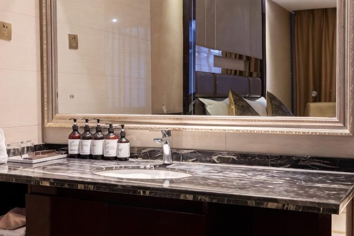 Un tocador de mármol con un espejo grande, un lavabo y una botella de jabón para manos.