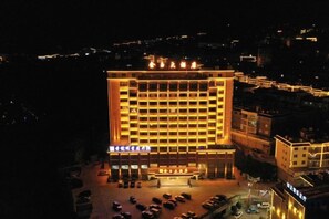 A multi-story hotel with a central courtyard, multiple floors, and a well-lit facade. - Jinyu Hotel (Weixi)