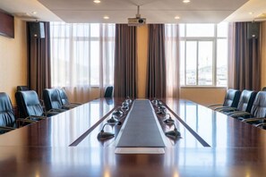A conference room with a long table, chairs, and a projector screen. - Jinyu Hotel (Weixi)