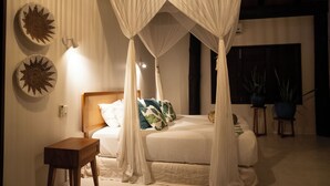 A bedroom with a canopy bed, bedside tables, decorative wall art, and potted plants.