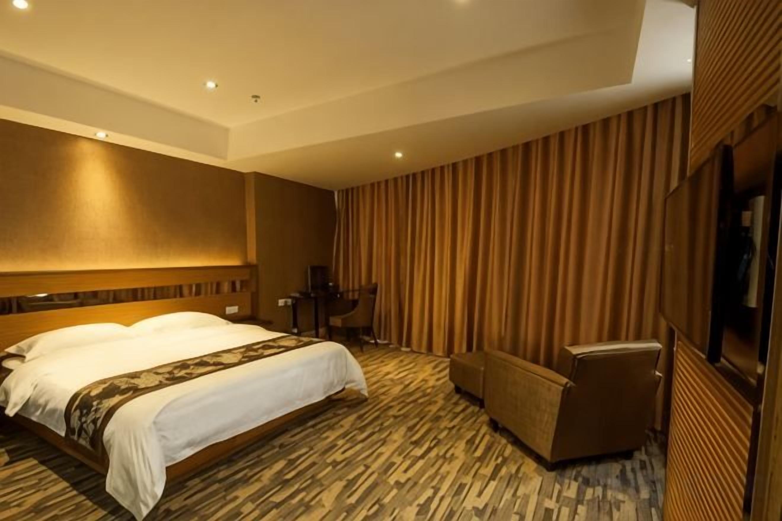 A hotel room with a large bed, a desk, and a seating area.