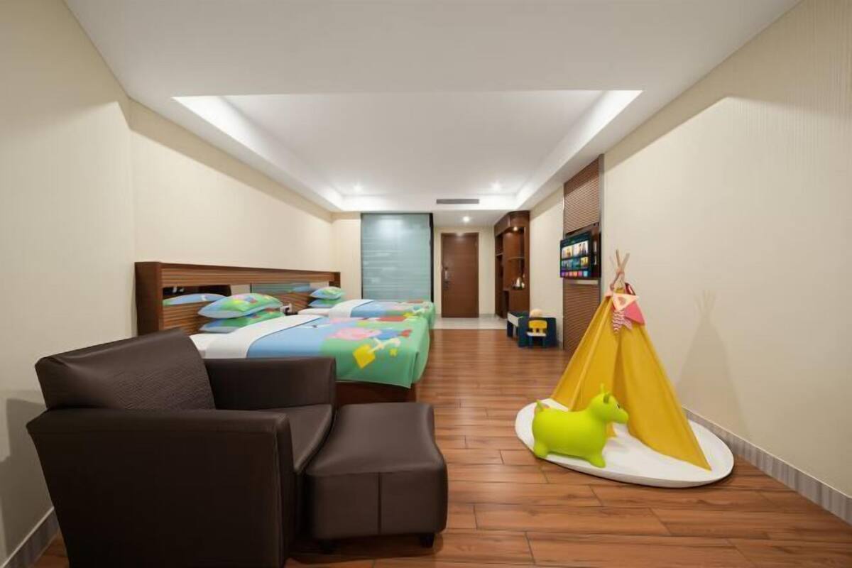 Una habitación de hotel con cama, sofá, una mesita, una silla y una estructura parecida a una tienda de campaña.