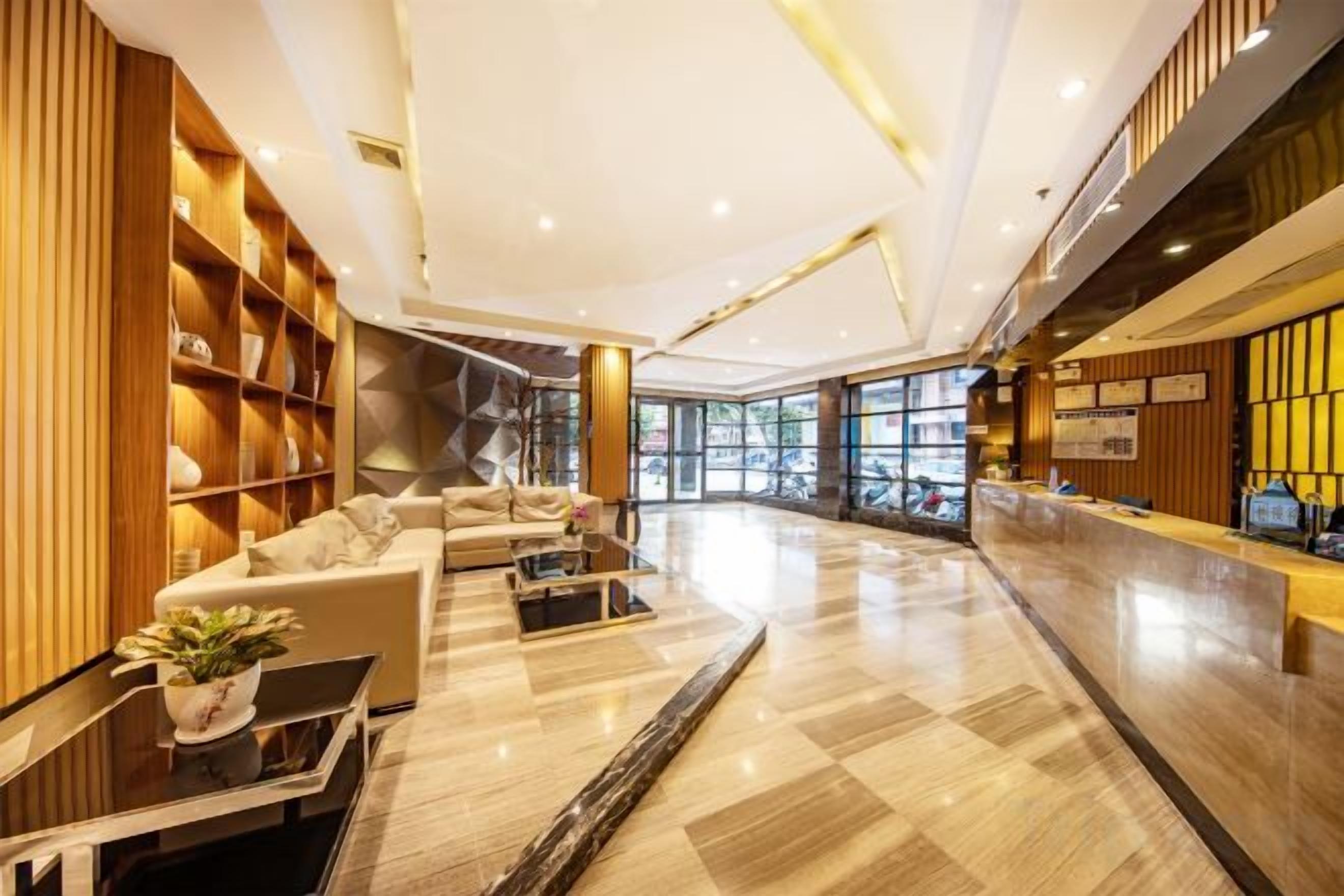 Un moderno vestíbulo de hotel con una recepción, zona de estar y un ventanal que proporciona luz natural.