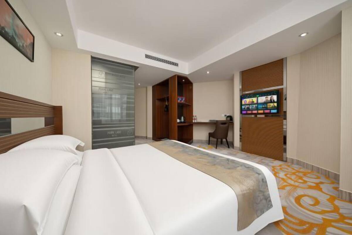 Una habitación de hotel con cama, escritorio, televisión y minibar.