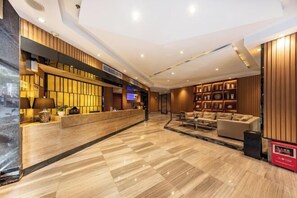 A modern hotel lobby with a reception desk, seating area, and decorative shelves. - Park Lane Yiju Hotel (Taishan Commercial City Qiaohu Road) (Taishan)