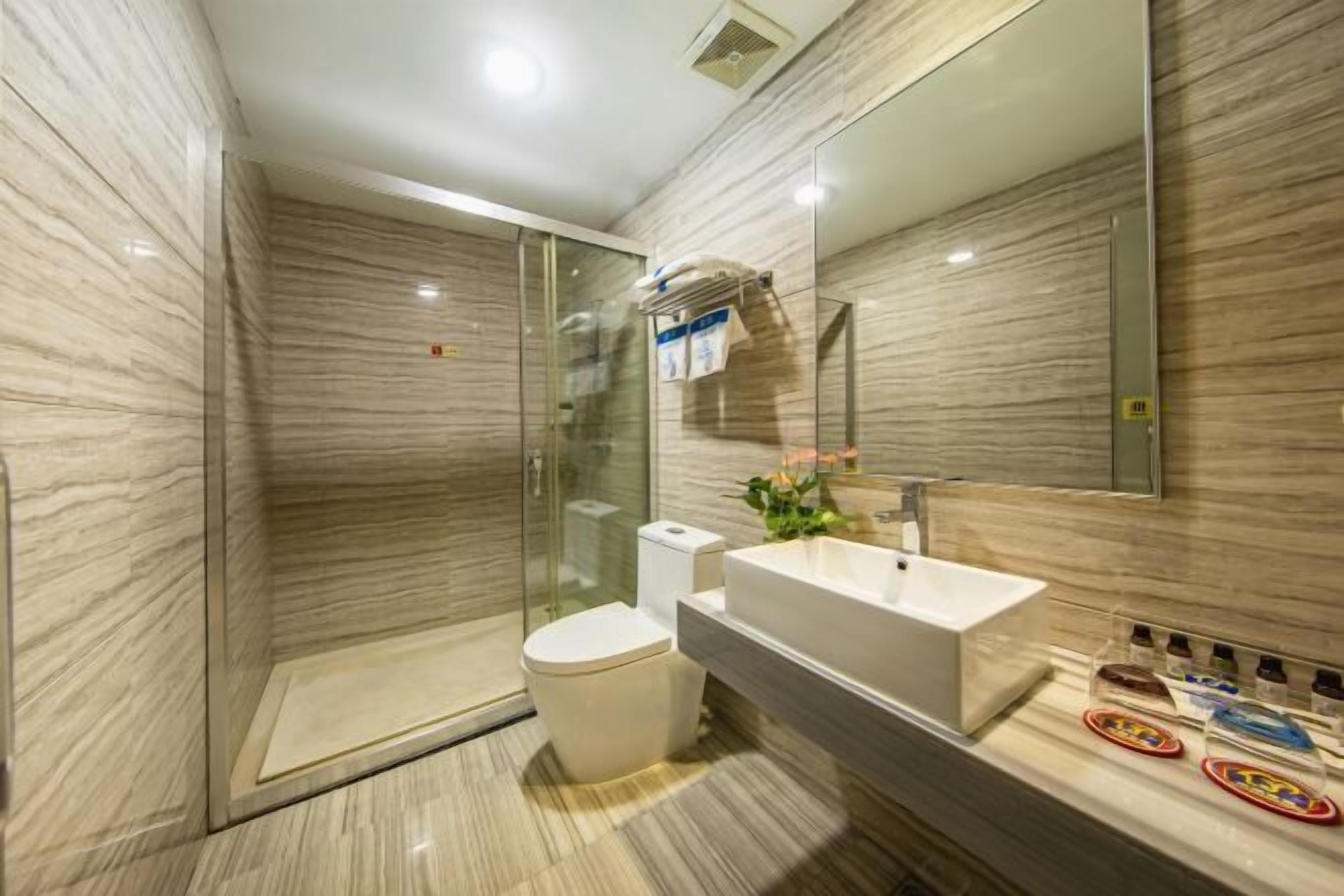 A modern bathroom with a glass-enclosed shower, a white toilet, and a large mirror above a sink.