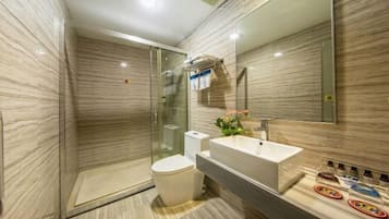 Un baño moderno con ducha de vidrio, inodoro blanco y un espejo grande sobre el lavabo.